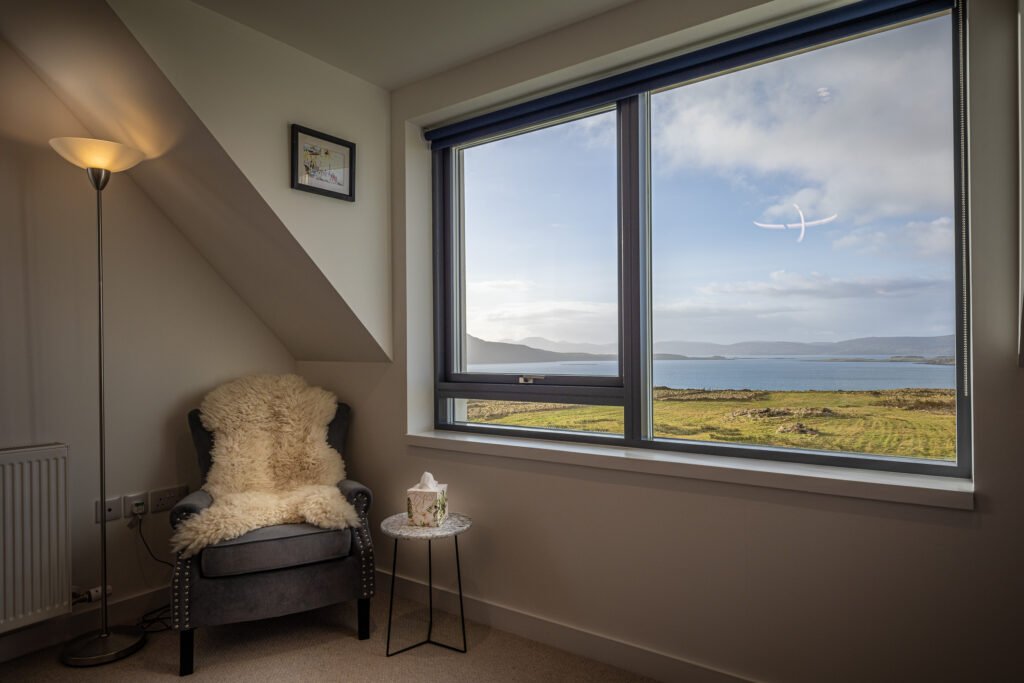 A comfy chair lined with sheepskin, next to the sea view from one of Long View's upstairs bedrooms