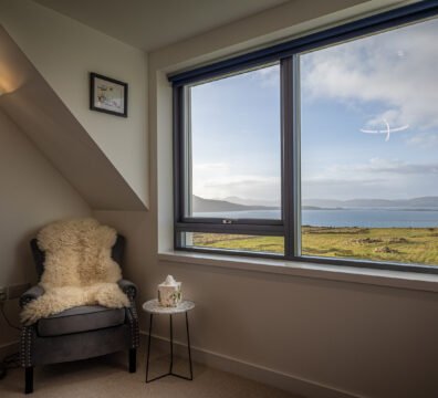 A comfy chair lined with sheepskin, next to the sea view from one of Long View's upstairs bedrooms