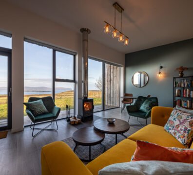 A stylish modern living room featuring luxury furnishings and expansive sea views from Silverwood, a two person Skye and Shore property